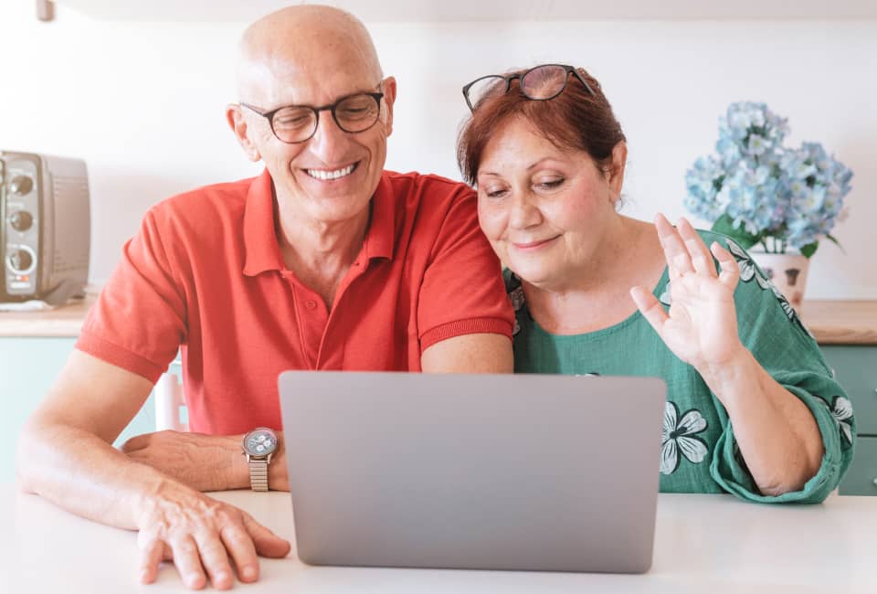 Älteres Ehepaar sitzen vor Laptop in winken in Laptop
