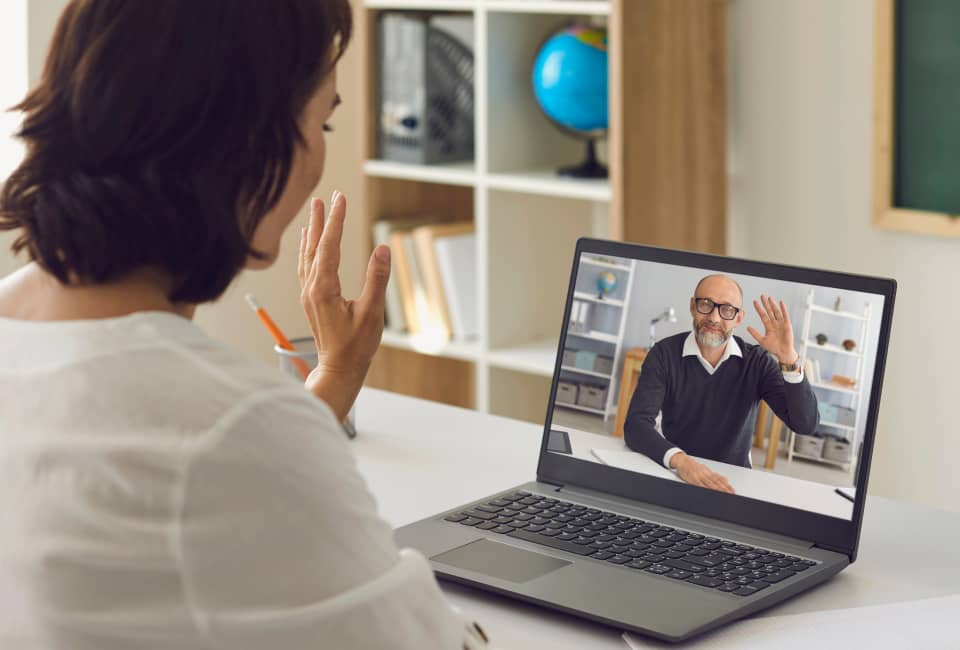 Frau sitzt vor ihrem Laptop und spricht in einer Videokonferenz mit einem Mann