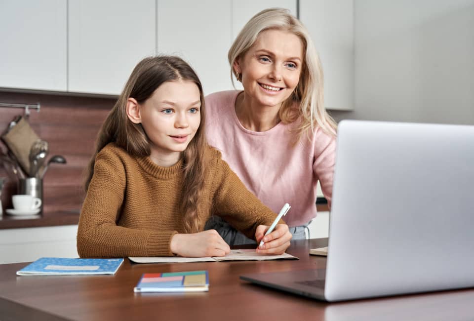 Mutter und Kind sitzen vor einem Laptop und lernen
