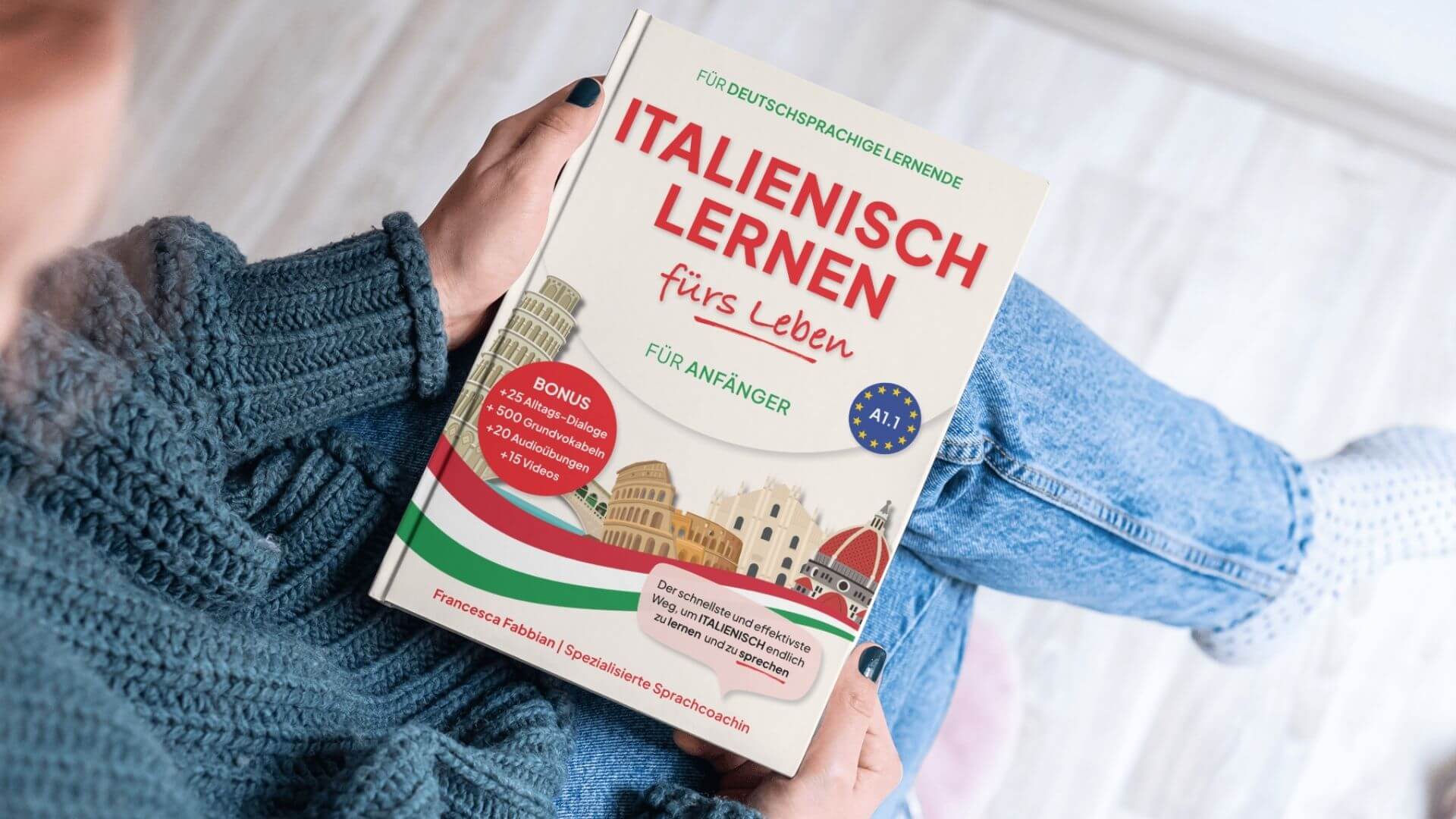 Person hält ein Italienisch-Lehrbuch mit dem Titel "Italienisch lernen fürs Leben – Für Anfänger“ in der Hand. Das Buch enthält Bonusmaterial wie Alltagsdialoge, Grundvokabeln, Audioübungen und Videos.