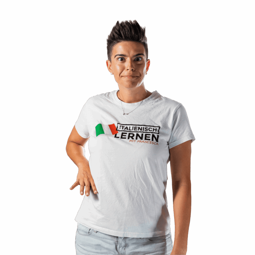 Person mit kurzen dunklen Haaren, die ein weißes T-Shirt mit der Aufschrift "Italienisch Lernen Mit Francesca" trägt, auf dem die italienische Flagge abgebildet ist. Sie steht vor einem schlichten Hintergrund und macht die ikonische "Che fame"-Geste.