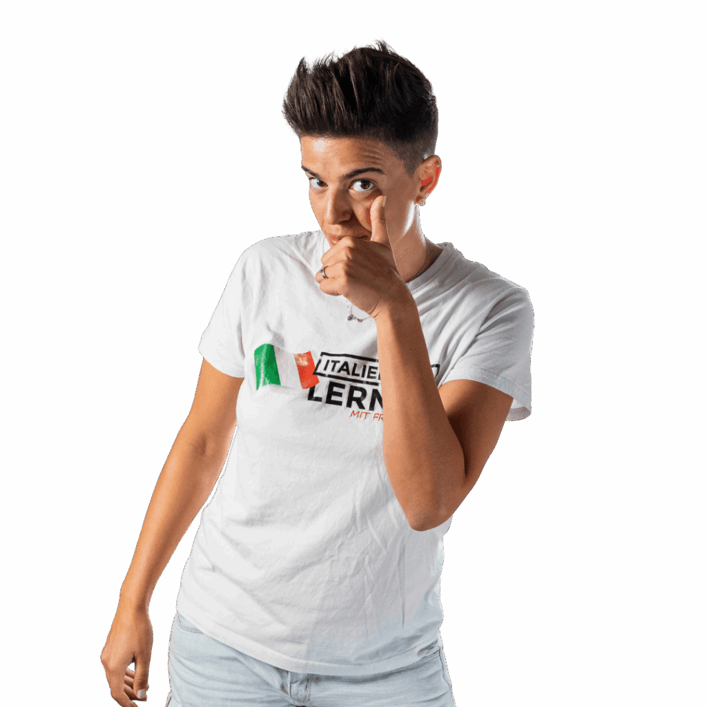 Eine Person mit kurzen Haaren und weißem T-Shirt macht die Geste "Fatti furbo", während sie auf die Kamera zeigt, vor einem transparenten Hintergrund.