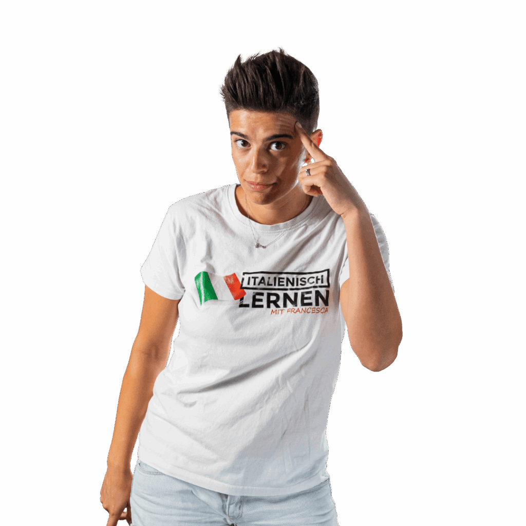 Eine Person mit kurzen Haaren, die ein weißes T-Shirt mit der Aufschrift "Italienisch Lernen Mit Francesca" trägt, macht die Geste "Sei pazzo", indem sie auf ihren Kopf zeigt, und steht vor einem transparenten Hintergrund.