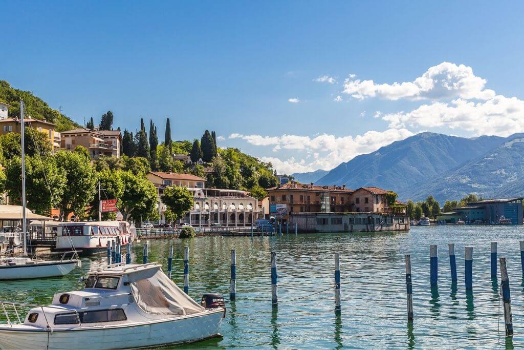 Typische Landschaft am Iseosee in der Lombardei mit Booten, Bergen, Bäumen und Wasser.