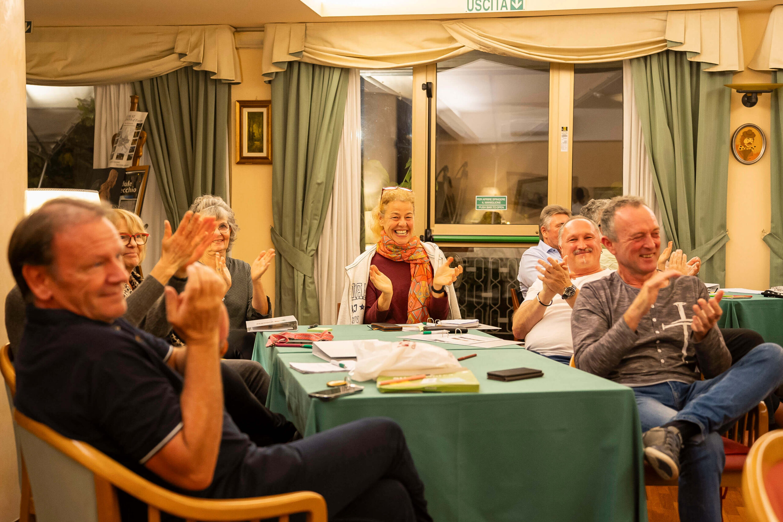 Gruppe von Menschen im Hotel, die sich unterhalten, lächeln und applaudieren.