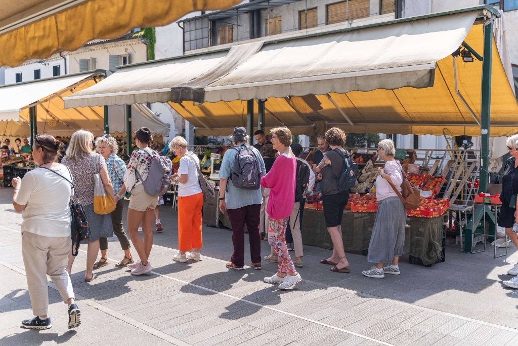 Gruppe von Menschen, die über den Markt in einer italienischen Stadt schlendern.