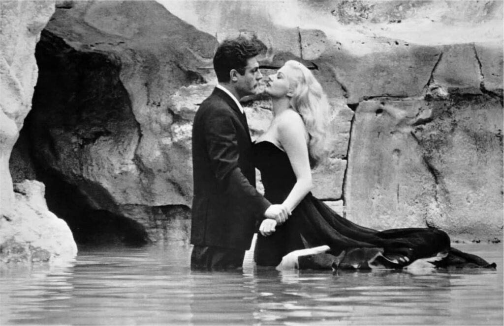 Schwarzweiß-Szene: Frau im eleganten Kleid und Mann stehen zusammen im Wasser.