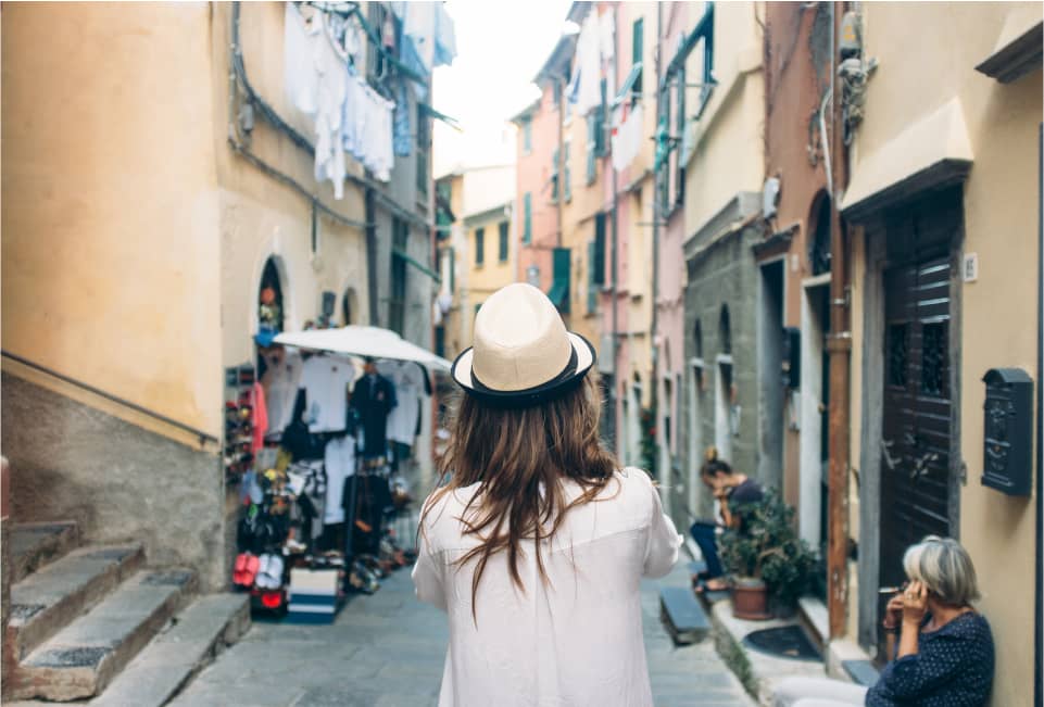 Frau mit Hut erkundet italienische Altstadtgasse