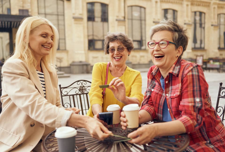 Drei lachende Frauen beim Kaffeetrinken auf Stadtplatz