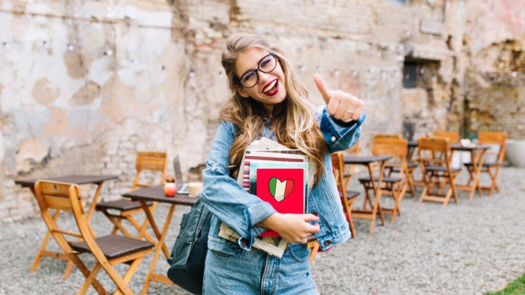 Junge Frau mit Brille, die glücklich ein Daumen-hoch zeigt, während sie ein Stapel von Notizbüchern hält.