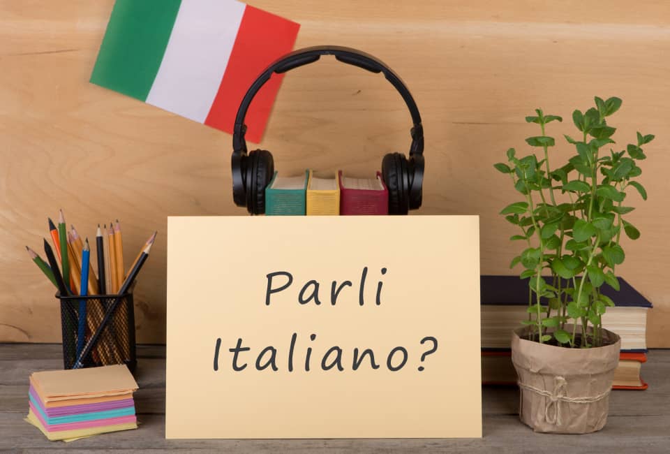 Schild „Parli Italiano?" mit Kopfhörern und Flagge