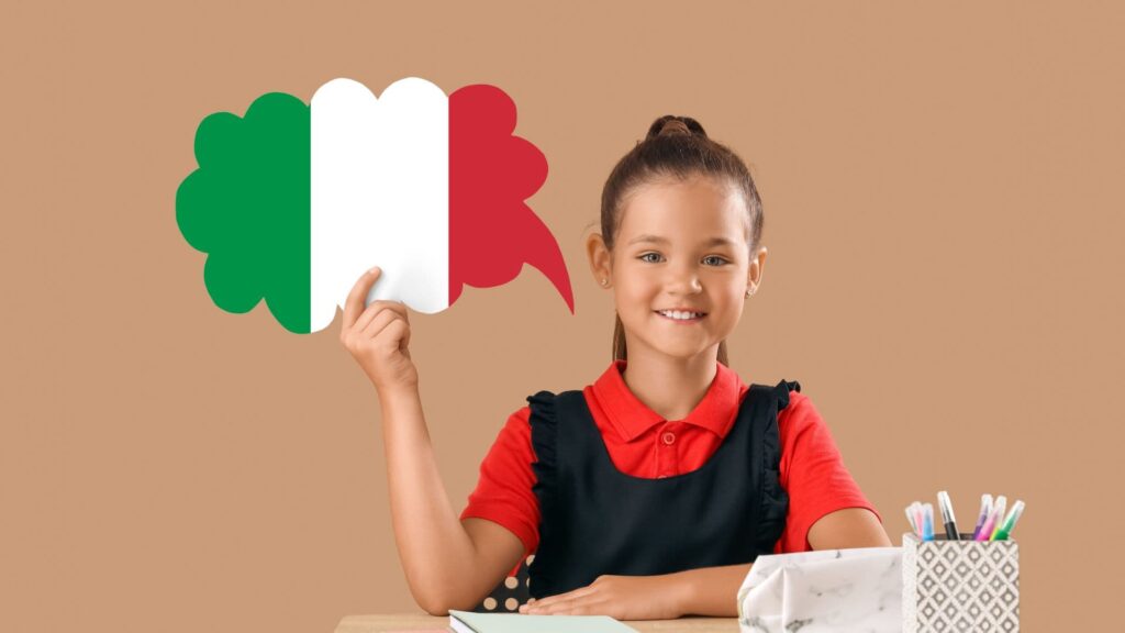 Ein Mädchen hält ein Sprechblasen-Symbol mit der italienischen Flagge in der Hand und lächelt dabei, während sie vor einem beige-farbenen Hintergrund sitzt.